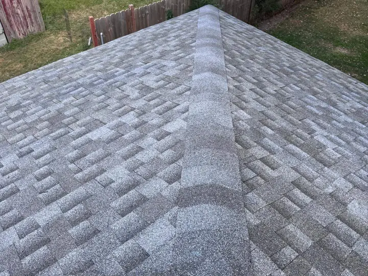 Hip-cap shingles where two gray shingle roof slopes meet