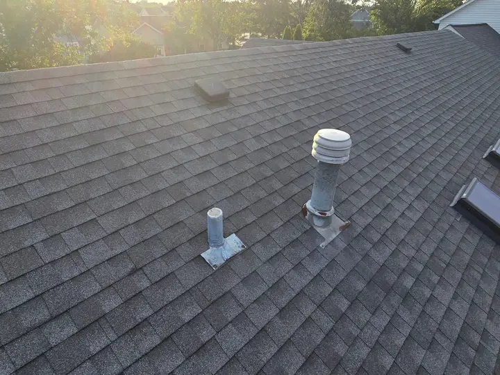 Vent pipes and flashing surrounded by shingles near two skylights