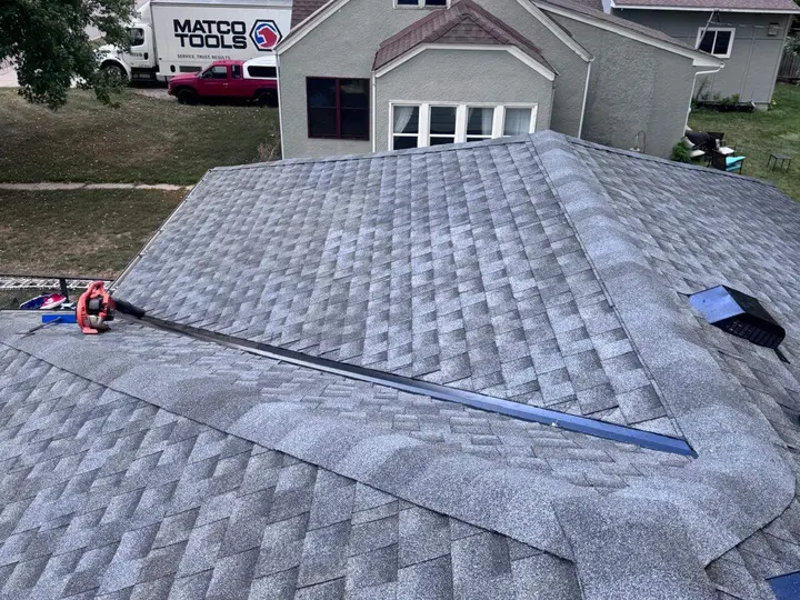Shingled roof slopes meeting at a metal-lined valley