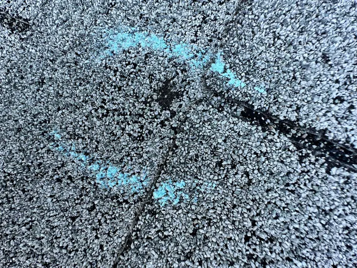 Close-up of an asphalt shingle with a blue chalk inspection marking