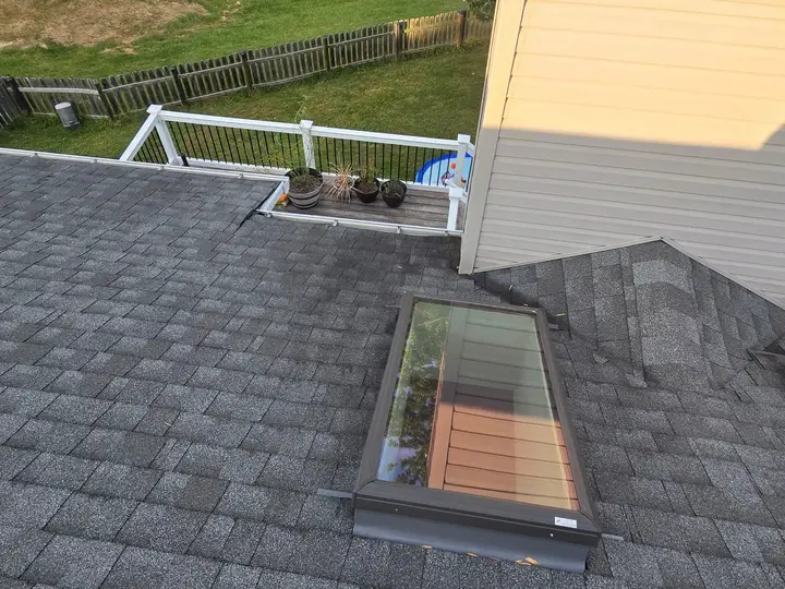 Two skylights beside a sided chimney enclosure on a shingle roof