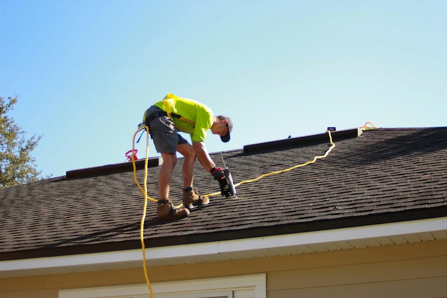 A roofer installing dark asphalt shingles
